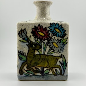 May include: A rectangular ceramic vase with a narrow neck and a cream-colored, crackled glaze. The front features a painted scene of a deer among colorful flowers in red, blue, and yellow, with green foliage. The vase is a decorative item.