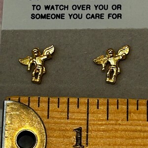 Pode incluir: Duas estatuetas de anjo douradas com as asas abertas, sobre um fundo branco com o texto "GUARDIAN ANGELS TO WATCH OVER YOU OR SOMEONE YOU CARE FOR".