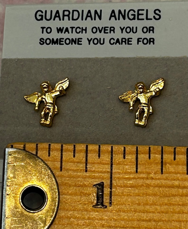 Pode incluir: Duas estatuetas de anjo douradas com as asas abertas, sobre um fundo branco com o texto "GUARDIAN ANGELS TO WATCH OVER YOU OR SOMEONE YOU CARE FOR".