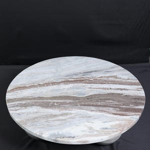 Op de afbeelding: Een ronde marmeren salontafel met een wit, bruin en grijs patroon. De tafel heeft een stevige basis en een glad, gepolijst oppervlak. De tafel heeft een diameter van ongeveer 122 cm.