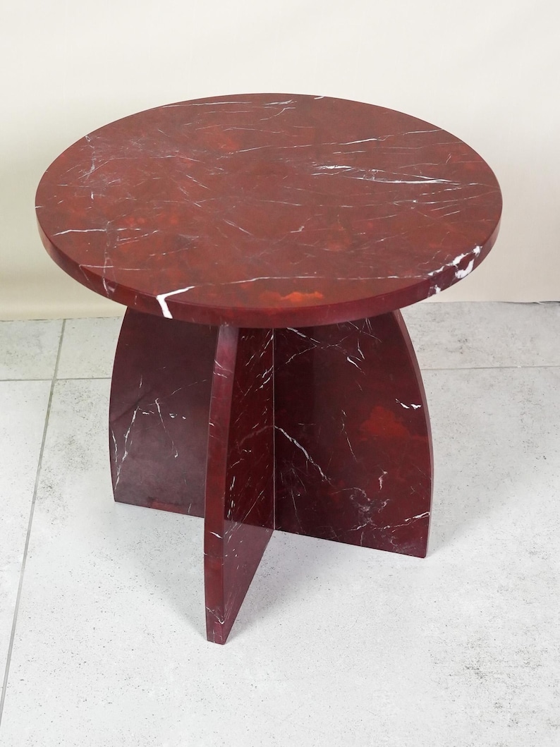 May include: A round, red marble side table with white veining. The tabletop is supported by a pedestal base with three curved legs. The table is approximately 18 inches in diameter and 18 inches tall.