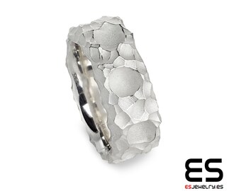 May include: A silver ring with a textured, hammered finish. The ring has a unique design with multiple circular shapes.