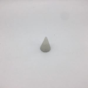 Puede incluir: Un objeto blanco con forma de cono y superficie texturizada.