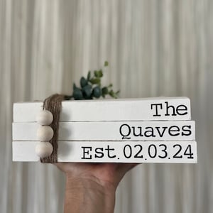 May include: White wooden stacked blocks with the text "The Quaves Est. 02.03.24" in black lettering. The blocks are decorated with a brown twine bow and white wooden beads.