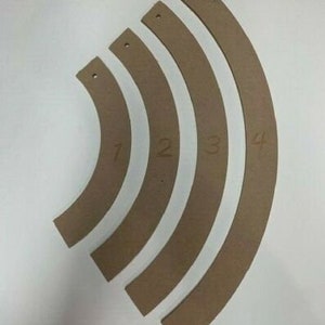 Pode incluir: Conjunto de cinco peças curvas de madeira castanho, numeradas de 1 a 4. As peças são de tamanhos diferentes e podem ser usadas para projetos de artesanato ou carpintaria.