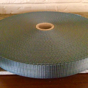 May include: A roll of gray nylon webbing, a type of strong, durable fabric often used for straps, belts, and other applications.