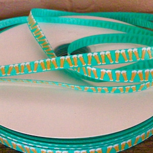 May include: A roll of turquoise ribbon with a repeating pattern of gold beer mugs.