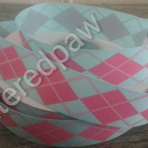 May include: A roll of light blue and pink ribbon with a diamond pattern. The ribbon is made of grosgrain and has a satin finish.