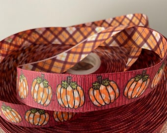 May include: A roll of red and orange ribbon with a plaid pattern on one side and a pumpkin pattern on the other side. The pumpkins are orange with white polka dots.