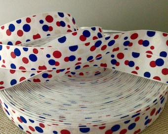 May include: White ribbon with red and blue polka dots. The ribbon is rolled up and the polka dots are visible on the outside of the roll.