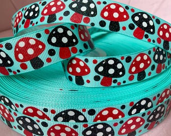 May include: A spool of turquoise grosgrain ribbon featuring a repeating pattern of glittery red and black mushrooms with white spots. The ribbon has a textured, ribbed surface and is wound into a tight coil, displaying the mushroom print throughout.