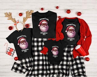 May include: Black and white checked pyjamas with a black t-shirt featuring a cartoon image of a Black Santa Claus with the text "Johnson Family Christmas 2023".