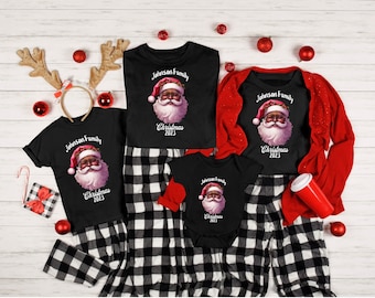 May include: Black and white checked pyjamas with a black t-shirt featuring a cartoon image of a Black Santa Claus with the text "Johnson Family Christmas 2023".