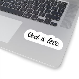 May include: A white sticker with black cursive writing that says "God is love." The sticker is on a silver laptop.