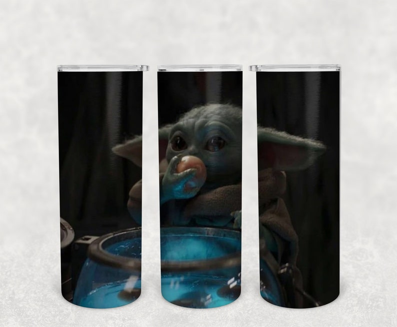 May include: Three stainless steel tumblers with a black background and a green alien character eating a small orange object. The alien is sitting in a blue container.