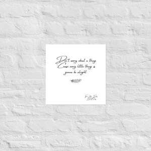 May include: A white square print with the quote "Don't worry about a thing, cause every little thing is gonna be alright" in black script. A feather illustration is below the quote. The print is against a white brick wall.