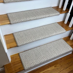 May include: A set of four beige and white chevron patterned stair treads. The treads are made of a soft, textured material and are designed to add a touch of style and safety to any staircase.