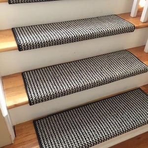 May include: Stair treads with a black and white houndstooth pattern. The treads are rectangular and have a black border. They are installed on wooden stairs with white risers.