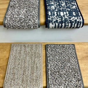 May include: Four carpet stair treads in a variety of colors and patterns. The top left tread is a speckled gray, the top right is a blue and white geometric design, the bottom left is a tan, and the bottom right is a speckled gray.