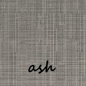 May include: Close-up of a textured fabric in shades of gray and off-white. The word "ash" is written in a cursive font across the bottom right corner of the fabric. The fabric has a woven appearance.