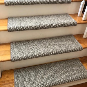May include: Four gray carpet stair treads with a textured surface. The treads are installed on wooden stairs.