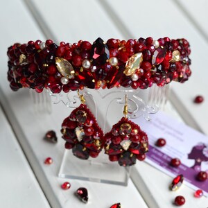 May include: A red and gold beaded headband and matching earrings. The headband has a comb attachment and the earrings are teardrop shaped.