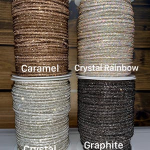 Puede incluir: Cuatro carretes de adorno de diamantes de imitaci&oacute;n dispuestos en una cuadr&iacute;cula. El carrete superior izquierdo est&aacute; etiquetado como Caramel, el superior derecho como Crystal Rainbow, el inferior izquierdo como Crystal y el inferior derecho como Graphite.