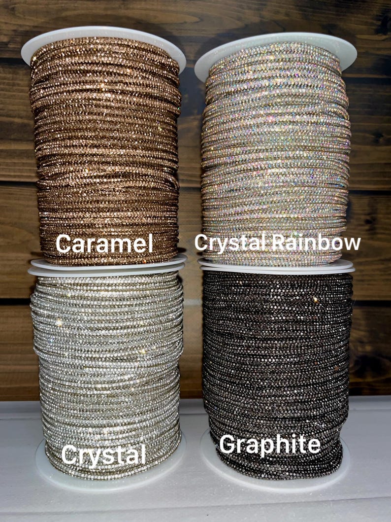 Puede incluir: Cuatro carretes de adorno de diamantes de imitaci&oacute;n dispuestos en una cuadr&iacute;cula. El carrete superior izquierdo est&aacute; etiquetado como Caramel, el superior derecho como Crystal Rainbow, el inferior izquierdo como Crystal y el inferior derecho como Graphite.