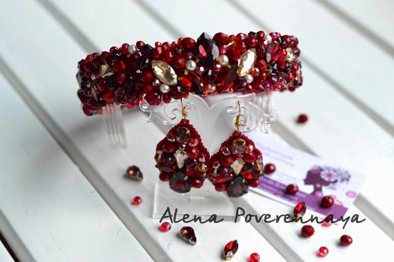 May include: A red and gold beaded headband with matching earrings. The headband is decorated with red and gold beads, as well as clear crystals. The earrings are also decorated with red and gold beads, and have a teardrop shape.