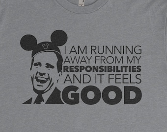 Könnte beinhalten: Ein heidefarbenes T-Shirt mit einer schwarzen Grafik eines Mannes mit Mickey-Mouse-Ohren. Der Text auf dem Shirt lautet "I am running away from my responsibilities and it feels GOOD".