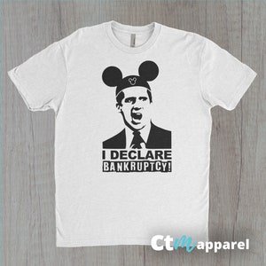May include: White t-shirt with a black and white image of a man wearing Mickey Mouse ears. The man is making a surprised expression and the text "I DECLARE BANKRUPTCY!" is below him.