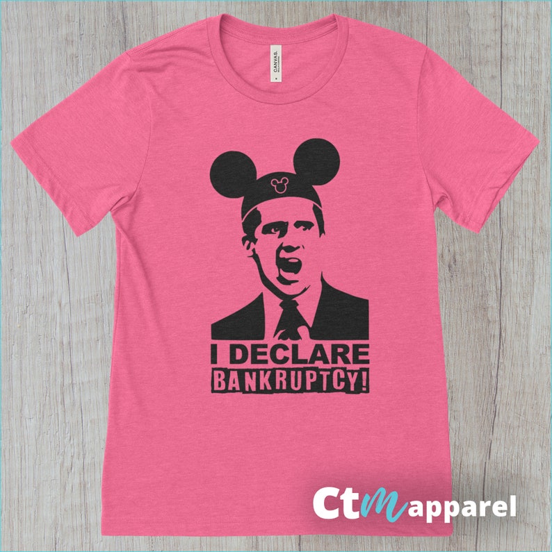May include: Pink t-shirt with a black and white image of a man wearing Mickey Mouse ears. The text "I DECLARE BANKRUPTCY!" is printed below the image.