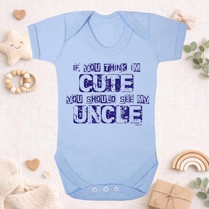 May include: A light blue baby onesie with the text "IF YOU THINK I'M CUTE YOU SHOULD SEE MY UNCLE" in dark blue. The onesie has short sleeves and three snaps at the bottom. A cute baby garment.