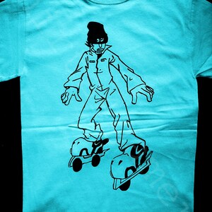 May include: A turquoise t-shirt with a black and white illustration of a person wearing a hat and roller skates.