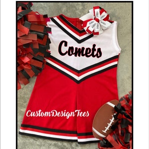May include: A red and white cheerleading uniform with the word "Comets" in black script. The uniform has black and white trim and is paired with a matching bow, a football, and red and black pom-poms. The text "Custom Design Tees" is also visible.