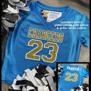 May include: A Columbia blue jersey with gold glitter lettering that reads "CHARGERS" and the number "23". The jersey has a white glitter outline. The image also includes a smaller jersey with the name "PARKER" and the number "23".