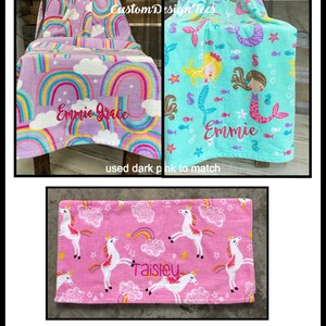 May include: Three fleece blankets with personalized embroidery. One is lavender with rainbows and the name "Emmie Grace". Another is turquoise with mermaids and the name "Emmie". The third is pink with unicorns and the name "Taisley".