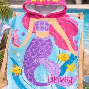 Pode incluir: Uma toalha de praia com capuz com um design de sereia. A toalha &eacute; azul com uma cauda de sereia roxa e cabelo rosa. O capuz &eacute; rosa com detalhes de estrelas amarelas. O nome "Lindsey" est&aacute; impresso na toalha. O texto "Custom Design Tees" est&aacute; no topo.