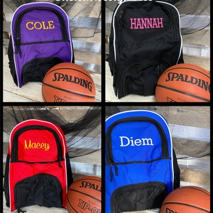 May include: Four different colored backpacks with white trim and black mesh pockets. Each backpack has a different name embroidered on the front in a contrasting color.  A basketball is in front of each backpack.