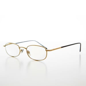 May include: Oval-lensed spectacles with gold-coloured frames. The design is delicate, with black temples and a gold bridge. The glasses are set against a white background, emphasising their sleek and minimalist aesthetic.
