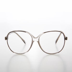 May include: Clear plastic framed eyeglasses with oval lenses.