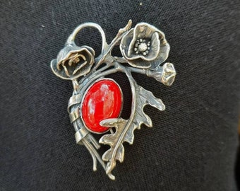 Elegant brooch with silver poppies and red stone