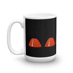 May include: White ceramic coffee mug with a black background and a graphic of three red pyramids with white lines on a black background.