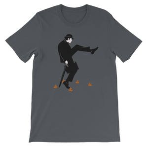 Könnte beinhalten: Ein dunkelgraues T-Shirt mit einer Silhouette eines Mannes im Anzug, der geht und auf einen Haufen Kot tritt. Der Mann trägt einen Hut und einen Regenschirm.