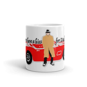 May include: White ceramic mug featuring a red and white illustration of a man in a trench coat standing next to a red sports car. The text "You have a kiss for Dad" is printed on the mug.