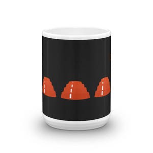 May include: White ceramic coffee mug with a black background and a repeating pattern of three orange stacked cones with white lines.