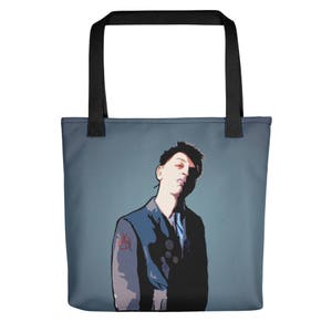 Könnte beinhalten: Eine Tragetasche mit einer stilisierten Illustration einer Person in einer blauen Jacke und einem roten Symbol auf dem Ärmel. Die Tasche hat schwarze Griffe und einen blauen Hintergrund.