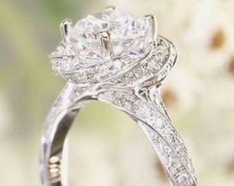May include: A silver engagement ring with a large, round, clear diamond center stone. The band is twisted and has a delicate, pave-set diamond halo around the center stone.
