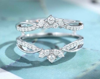 May include: A silver ring with a delicate, twisted design and a cluster of small, clear stones in the center. The ring is set with small, clear stones along the band.