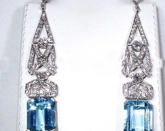 May include: A pair of long, silver dangle earrings with a geometric design and a large, rectangular aquamarine gemstone in the center of each earring.